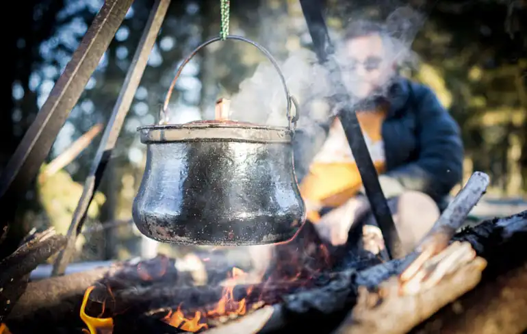 Rice cooking over a campfire, stainless steel cookware