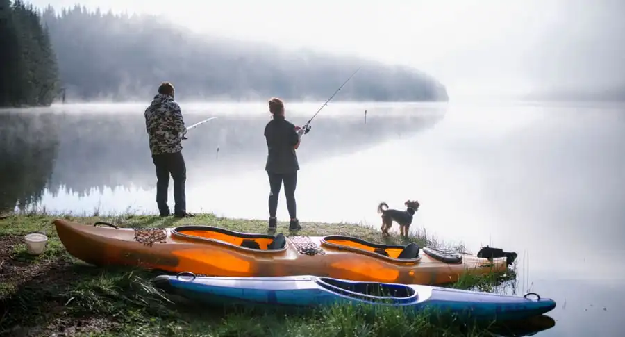 Couple is fishing at the mountains with their dog